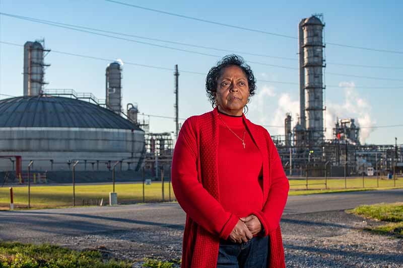 Sharon Lavigne stands in front of a chemical plant.