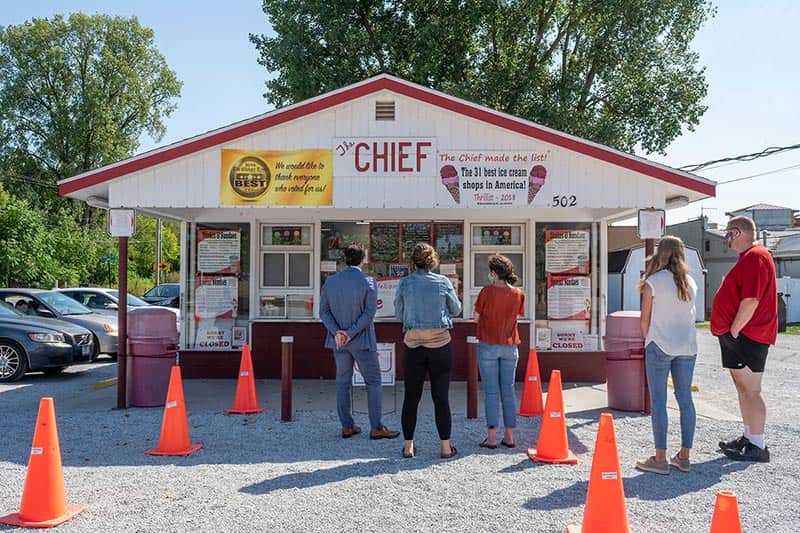 People stand and wait in line at a local ice cream shop.