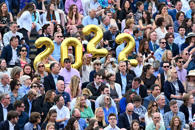 Crowd watching commencement ceremony while holding up '2022' baloons