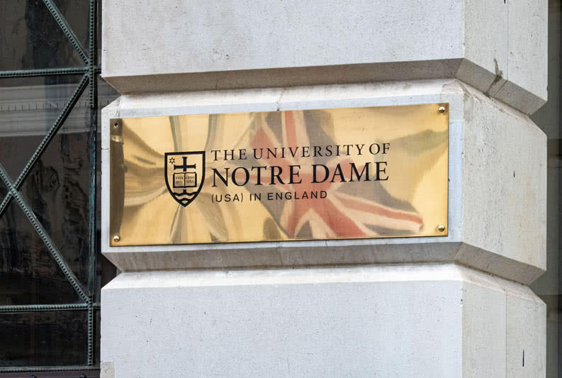 Brass University of Notre Dame sign with Union Jack reflection.