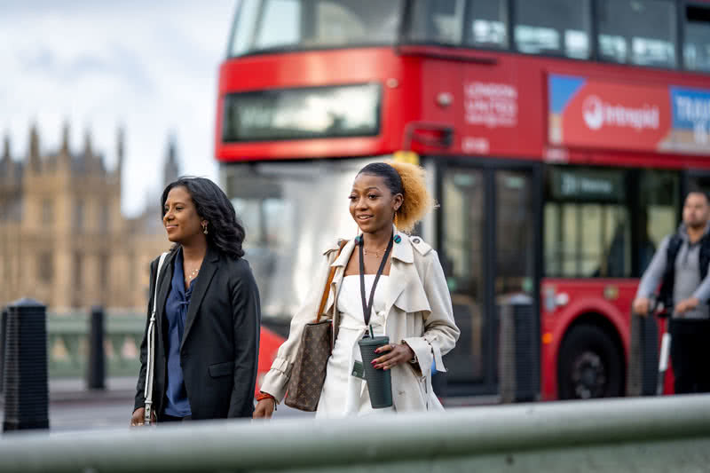 Students walking with on the Westminster Bridge with a double-decker bus is out of focus in the background.