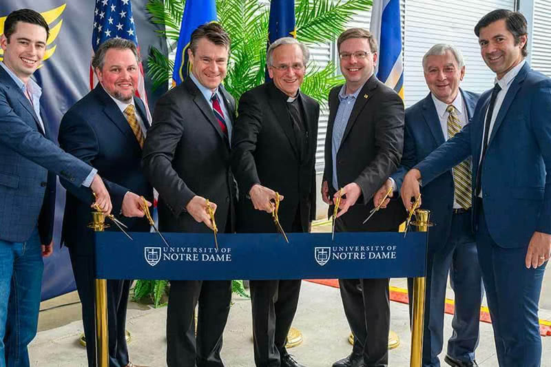 Ribbon cutting ceremony showing Fr. John I. Jenkins, C.S.C., the mayor of South Bend, Indiana, and others posing as they cut the ceremonial ribbon.