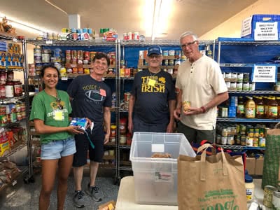 People stand in a stocked food pantry.