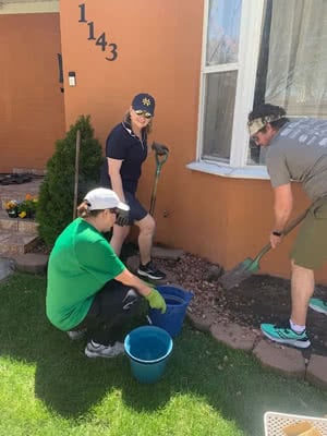 Several volunteers work on the landscaping in a front yard.