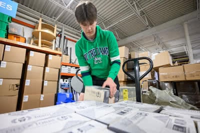 A man puts a box on a pallet in a warehouse.