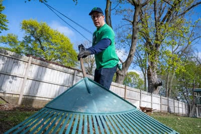 A man rakes a yard.