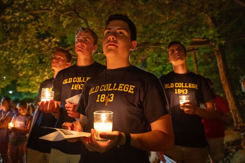 A group of students hold lit candles at the Grotto.