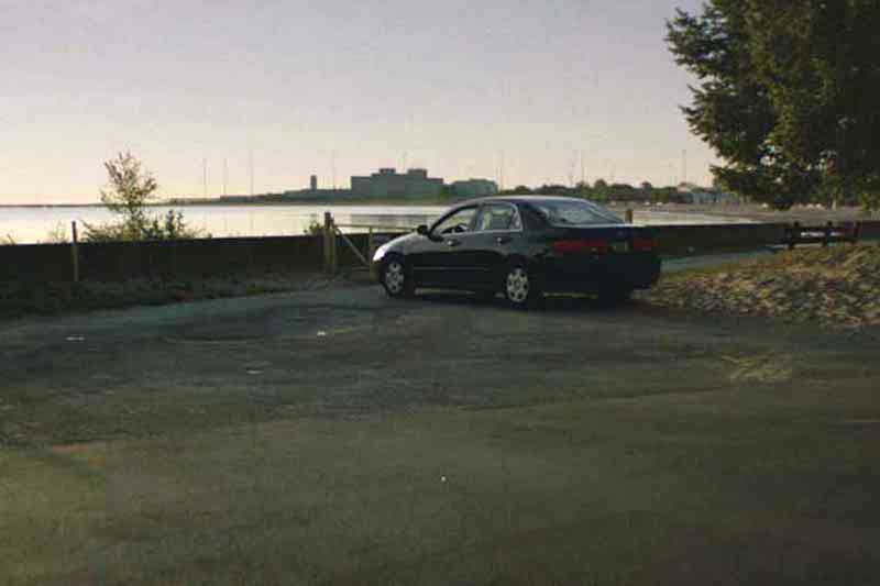 A car sits in an empty parking lot at dusk.