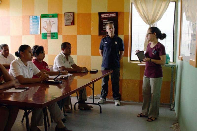 A woman presents with a male companion to a classroom of people.