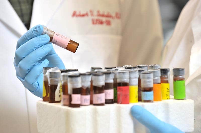 Gloved hands handle tubes of medicine.