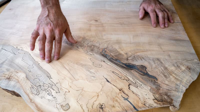 A close up of hands on a piece of wood with really defined wood grain. 