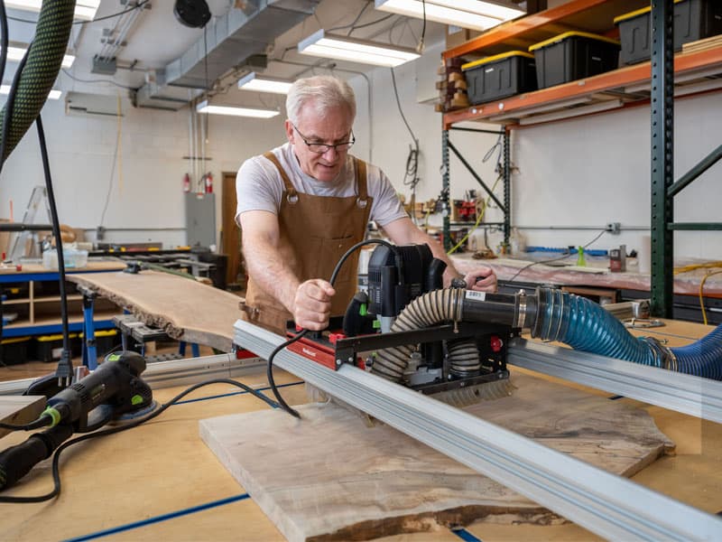 Fr. Dan Groody works on his table with a saw.