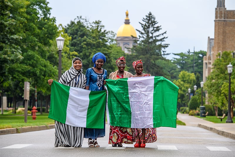 All four Nigerian girls standing in front of the dome holding 2 Nigerian flags.