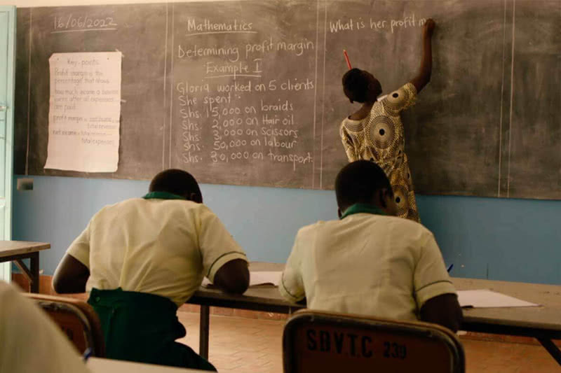 Victoria Nyangura stands in front of a chalkboard in a classroom