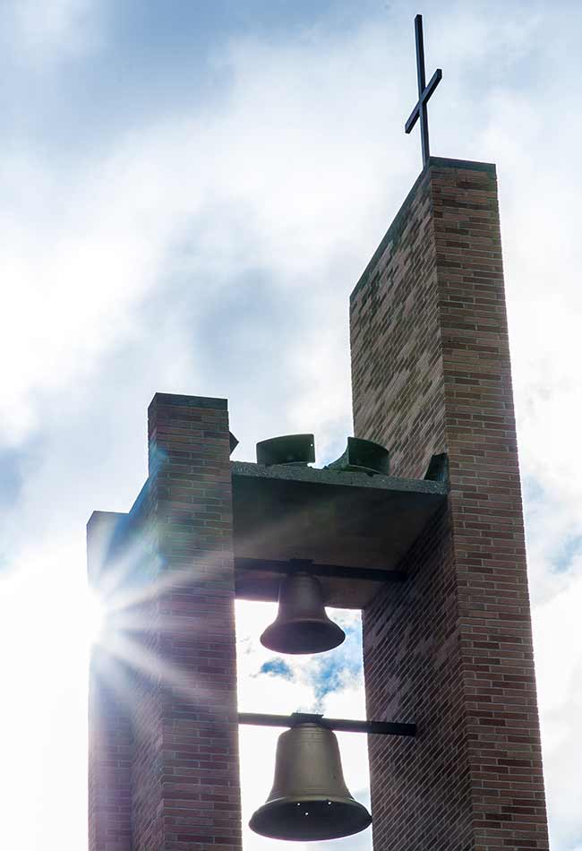The sun shining through a brick bell tower