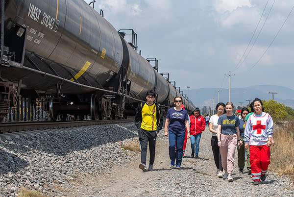 Students walk along a train track with members of the red cross in search of migrants who need assistance.