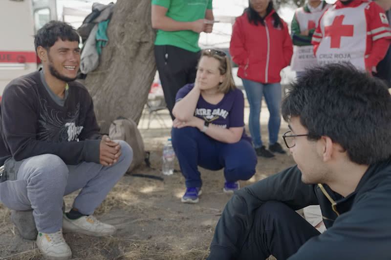 A migrant from Nicaragua sitting on a stone and speaking to Notre Dame students.