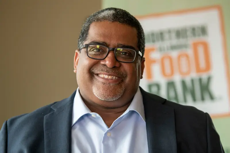 A portrait of Paul Henrys with a food bank sign behind him