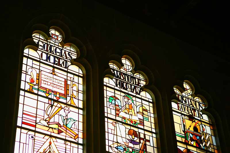 Stained glass windows against a black background in the O'Shaughnessy great hall.