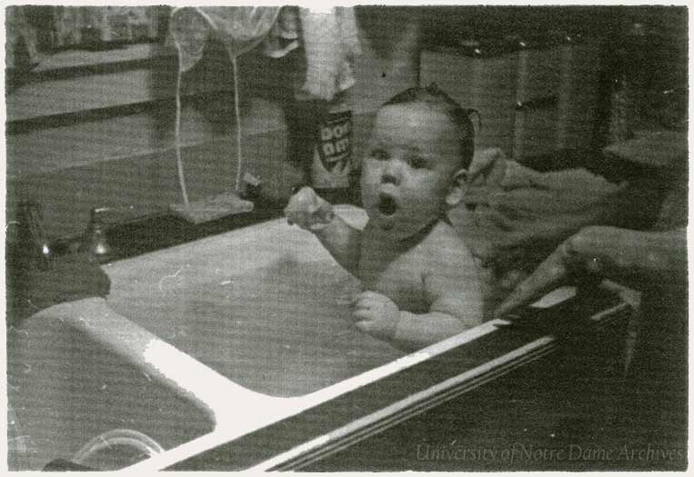A baby getting a bath in a kitchen sink, c1960.