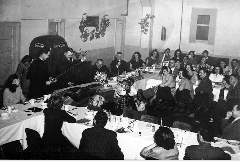 Vetville residents present Rev. Theodore M. Hesburgh with a fishing pole at a banquet that includes Rev. John J. Cavanaugh, March 1948.