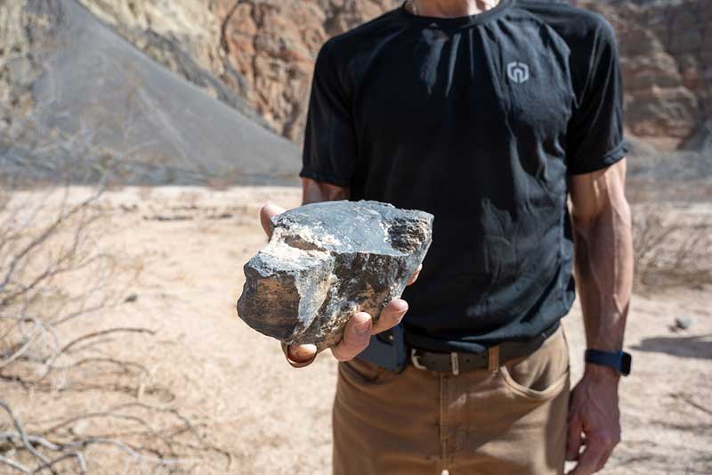 A man holds a large piece of rock up to the camera.
