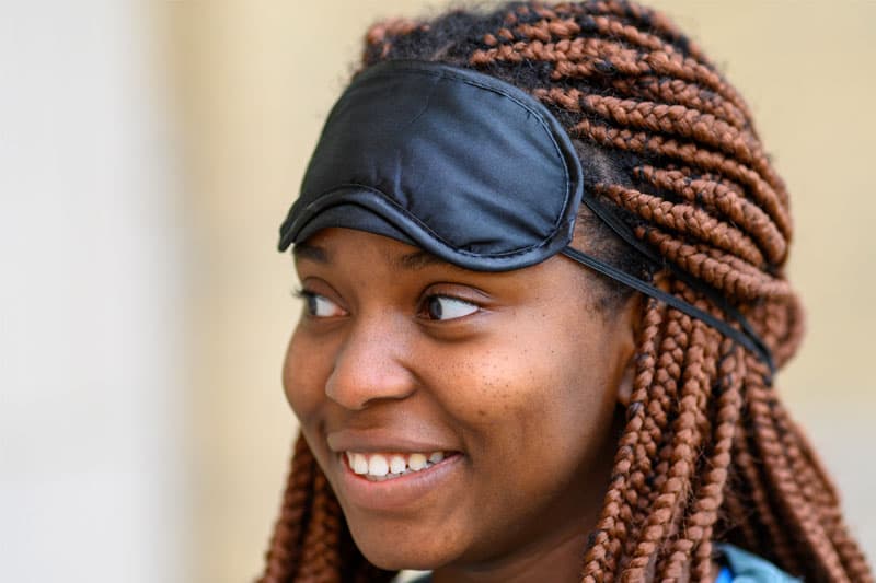 A close up of a women with a blindfold sitting on her forehead.