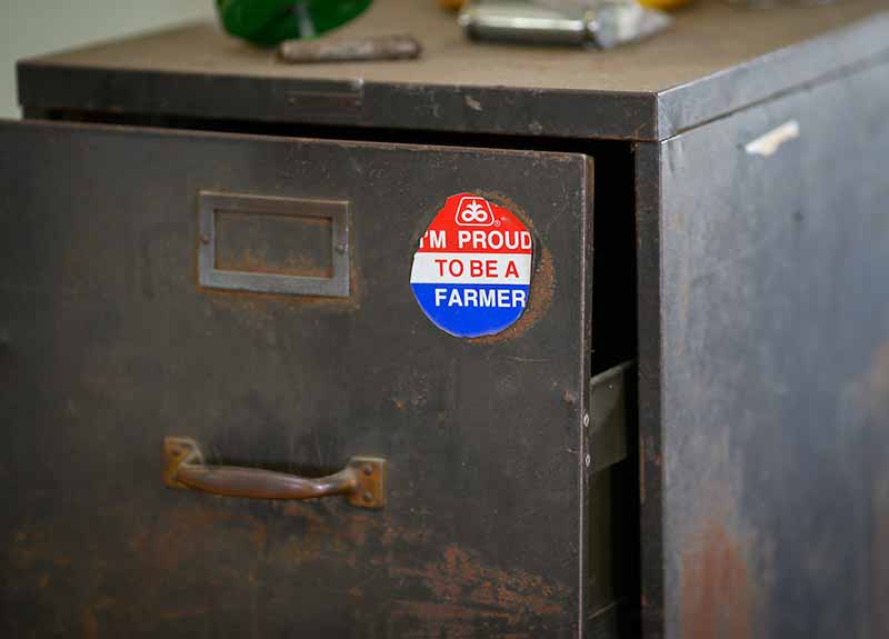 A sticker that says I'm a proud to be a farmer on a rusted file cabinet.