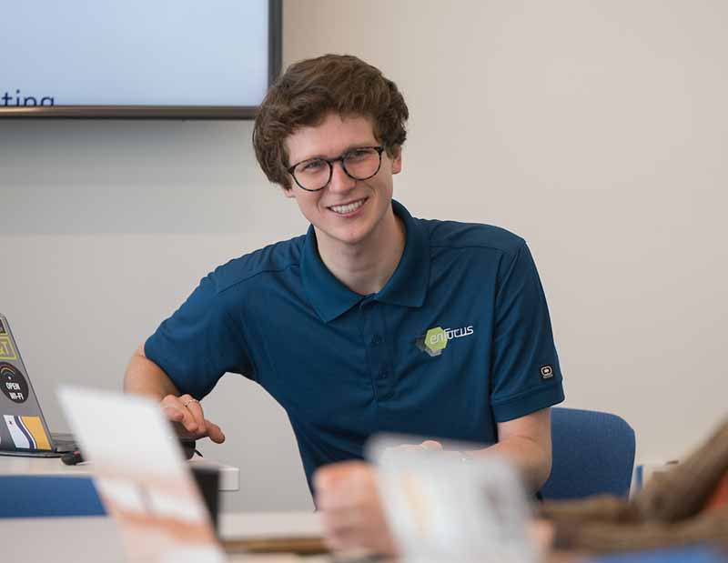 Patrick McGuire, a man wearing glasses and a blue polo shirt, smiles.