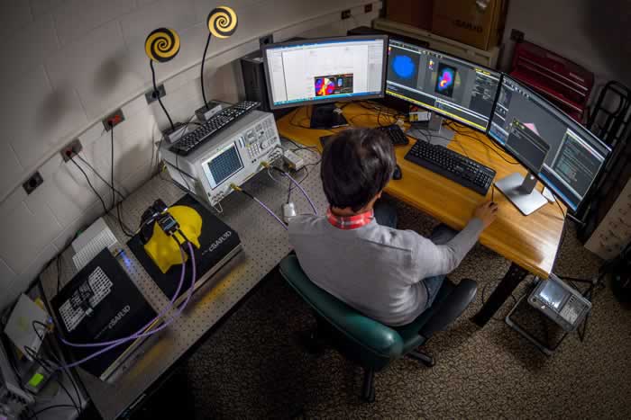 Overhead view of a man sitting at a computer desk with three monitors