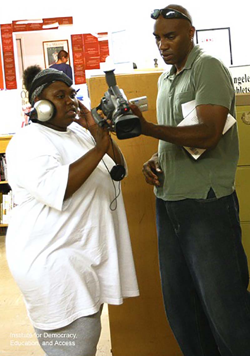 Morrell stands next to a student, both looking at a video camera.