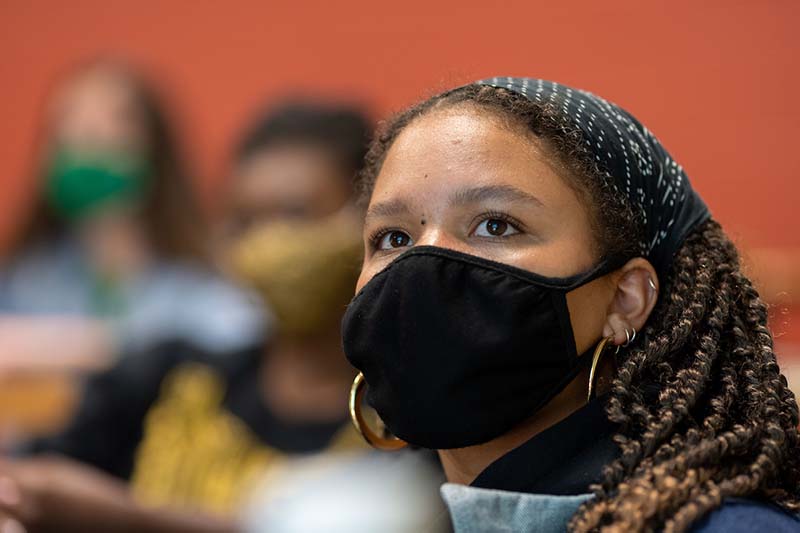 A female student wearing a face mask looks up.