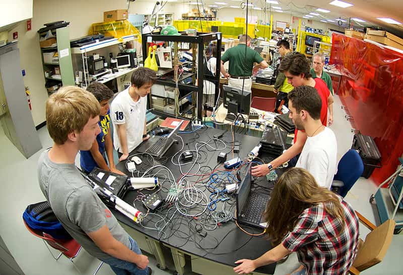 Students stand around a desk covered in wires.