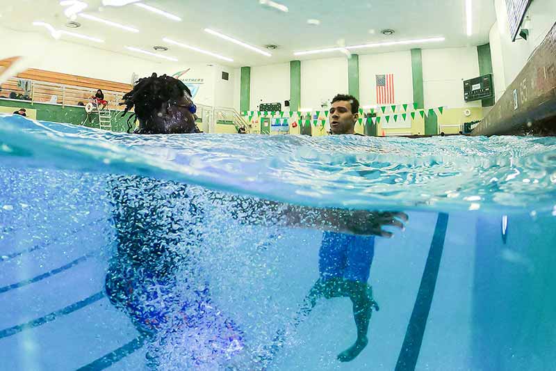 A half under water photo of a middle schooler and student athlete treading water.