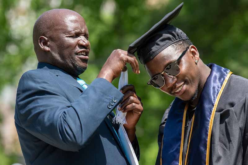 A father fixes his son's tassel on his graduation cap.