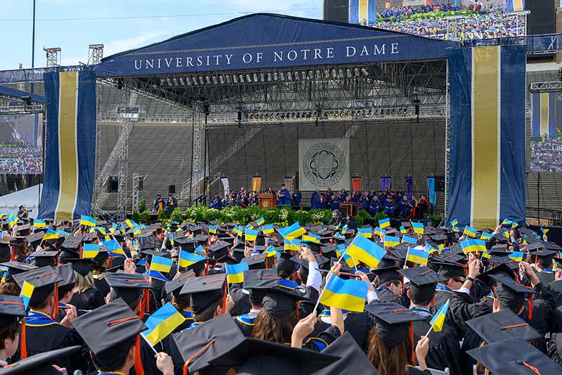 Graduates wave Ukrainian flags in tribute to Archbishop Borys Gudziak as he approaches the podium to give the Commencement address at the 2022 Commencement ceremony.