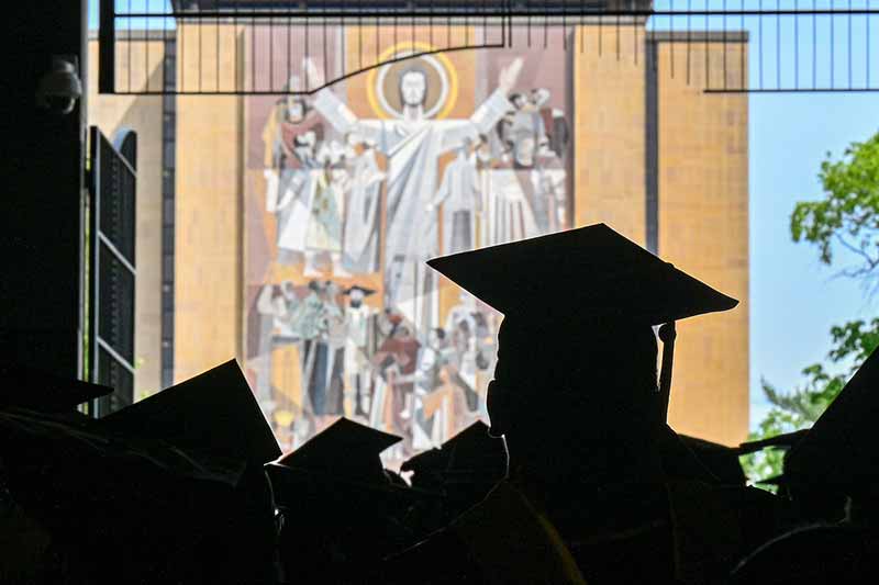 Silhouettes of graduate caps. The Word of Life Mural also known as Touchdown Jesus in the background.