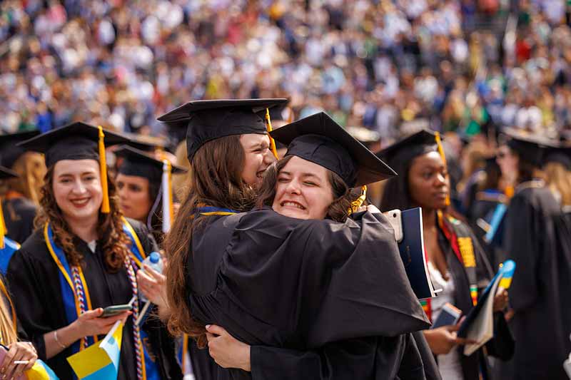 Two graduates hug each other during Commencement.