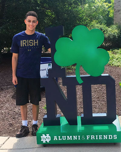 Austin Wyman stands next to a statue of the letters ND with a four leaf clover on it.