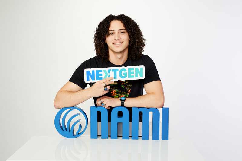 Austin Wyman poses holding a sign that says Next Gen.