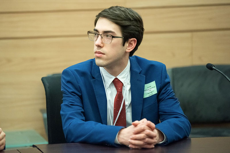 Blake Ziegler is dressed up in a suit and sitting at table.