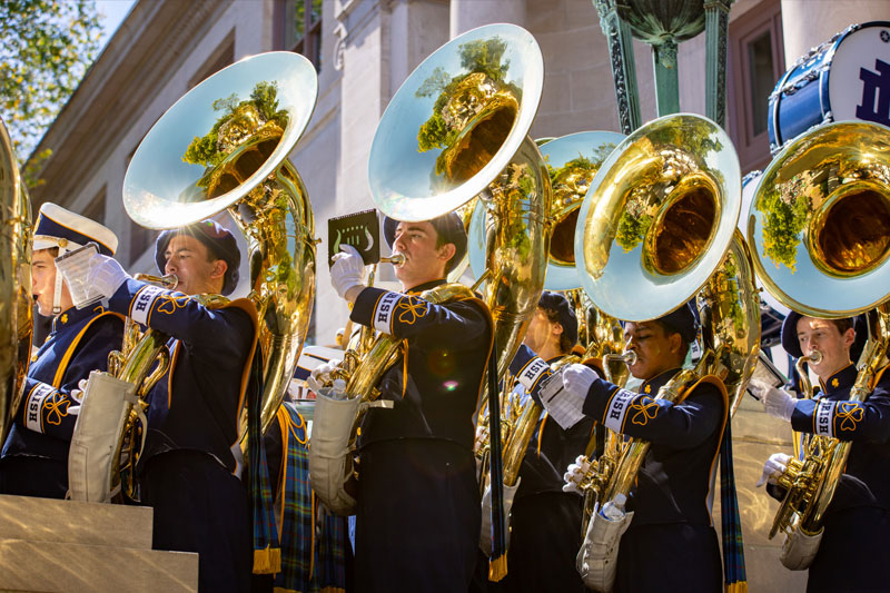 John Sexton stands holding his tuba with all the other tuba players in the marching band.