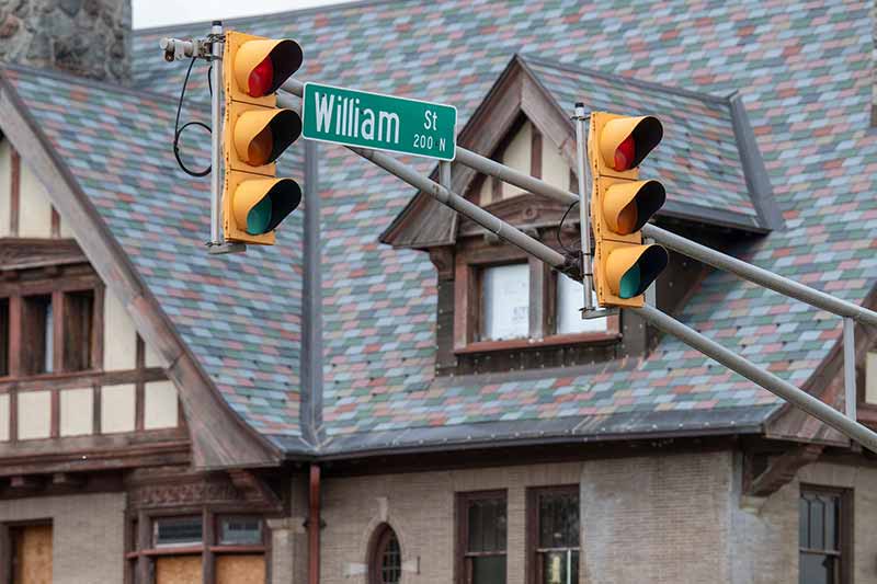 Traffic lights in the foreground with a sign that says William Street. A historic builing blurred out in the background.