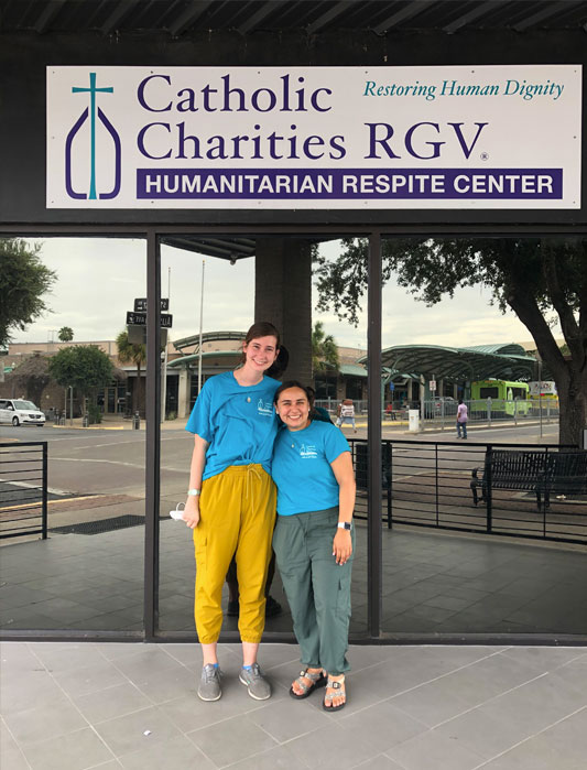 Two students stand outside the entrance to the Catholic Charities building.