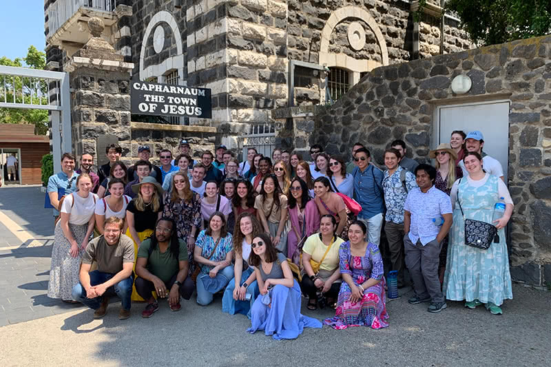 Group photo while standing in front of 'Capharnaum the town of Jesus' sign