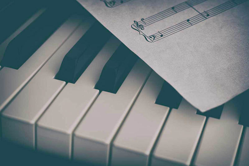 A close up of sheet music sitting on top of piano keys