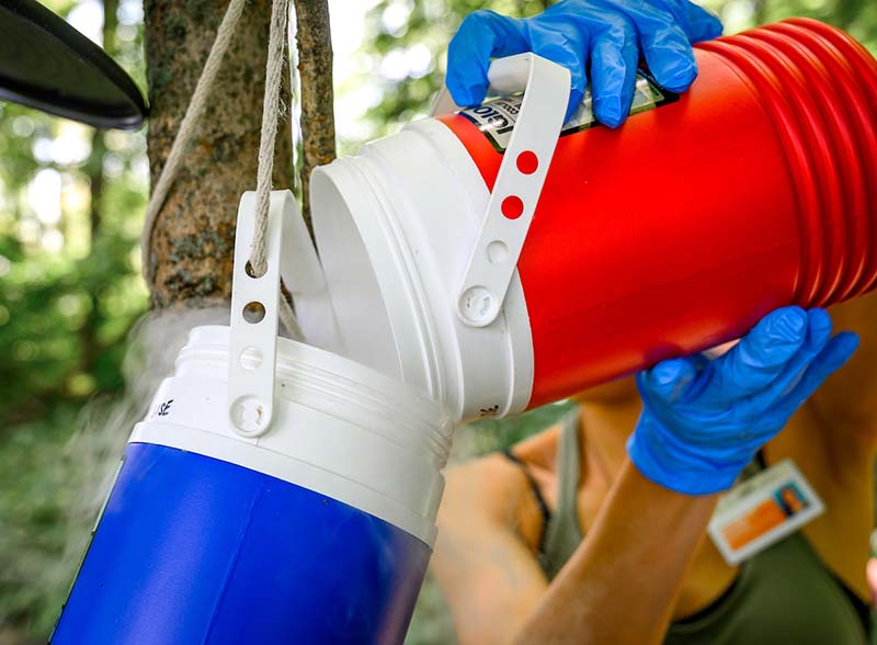 A student pours a red thermos of dry ice into a hanging blue thermos.