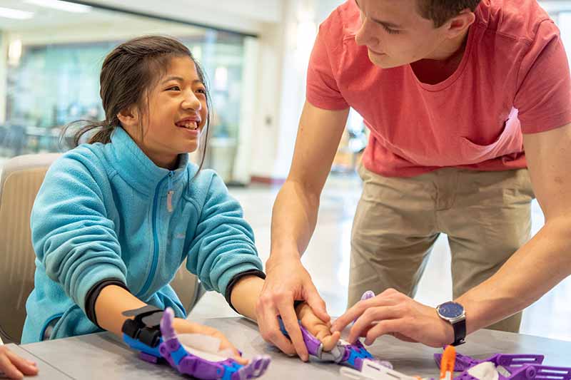 Cole Grabowski works with Tori on the final fitting of a pair of 3D-printed prosthetic hands.