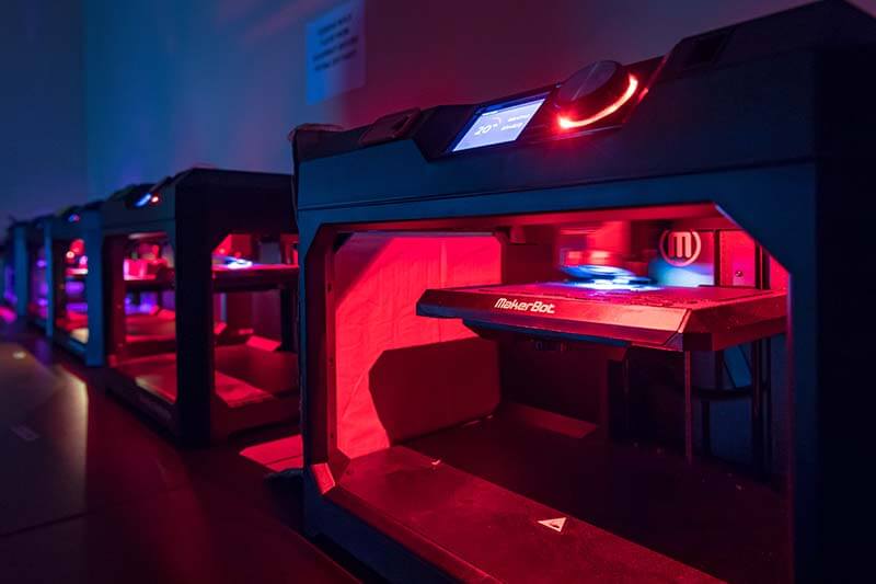 3D printers glow a pinkish red color in Fitzpatrick Hall of Engineering.