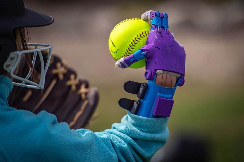 Tori throwing a softball with her new prosthetic hands.